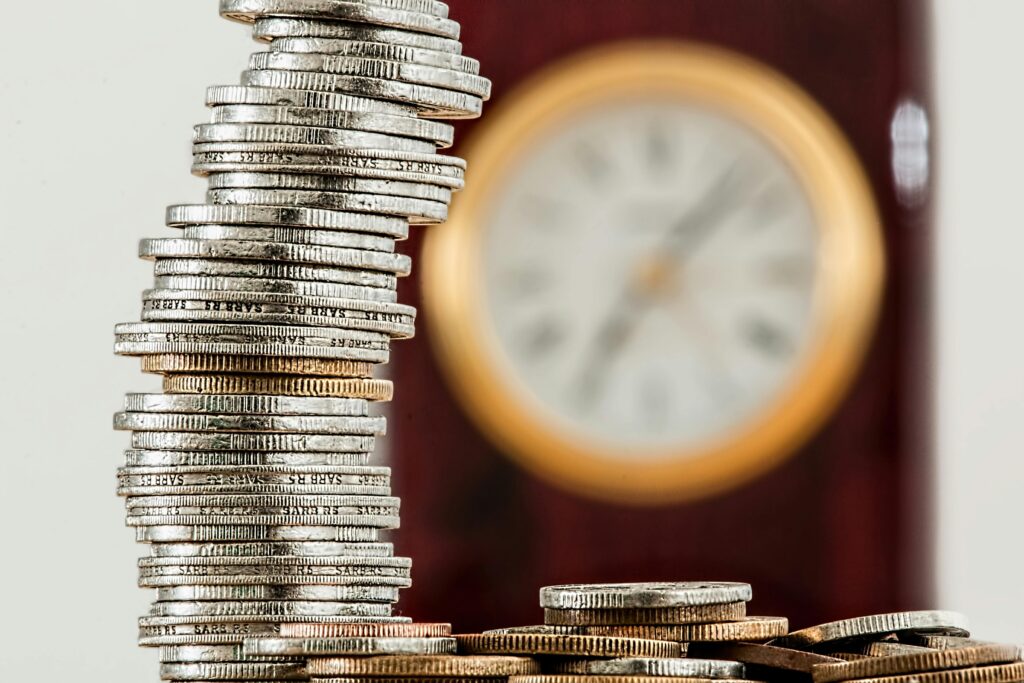 coins currency investment insurance 128867 128867 A close-up image of stacked coins with a blurred clock, symbolizing time and money relationship.